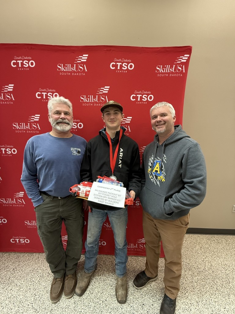 Mr. Lillis, a high school student and Mr. Johnson in front of the SkillsUSA banner smiling