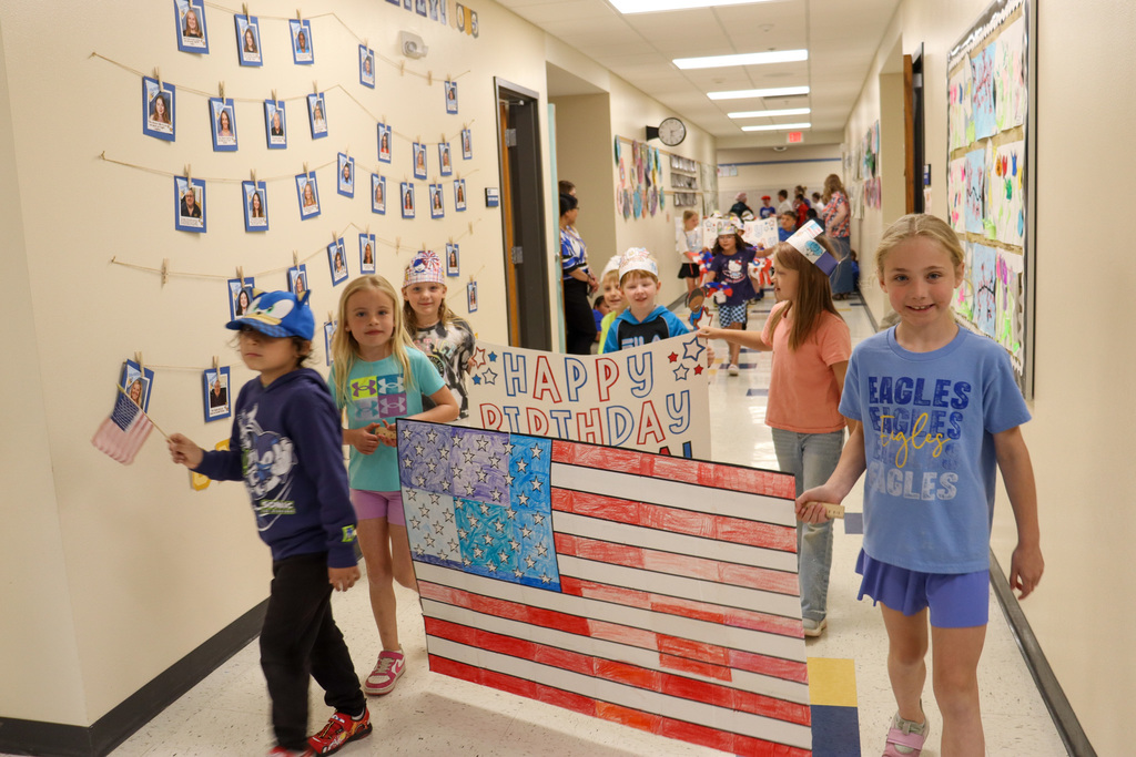 Mike Miller students carrying a U.S. flag banner in their parade