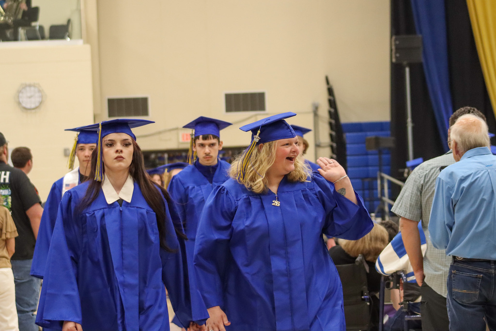 A graduate waving at a loved one
