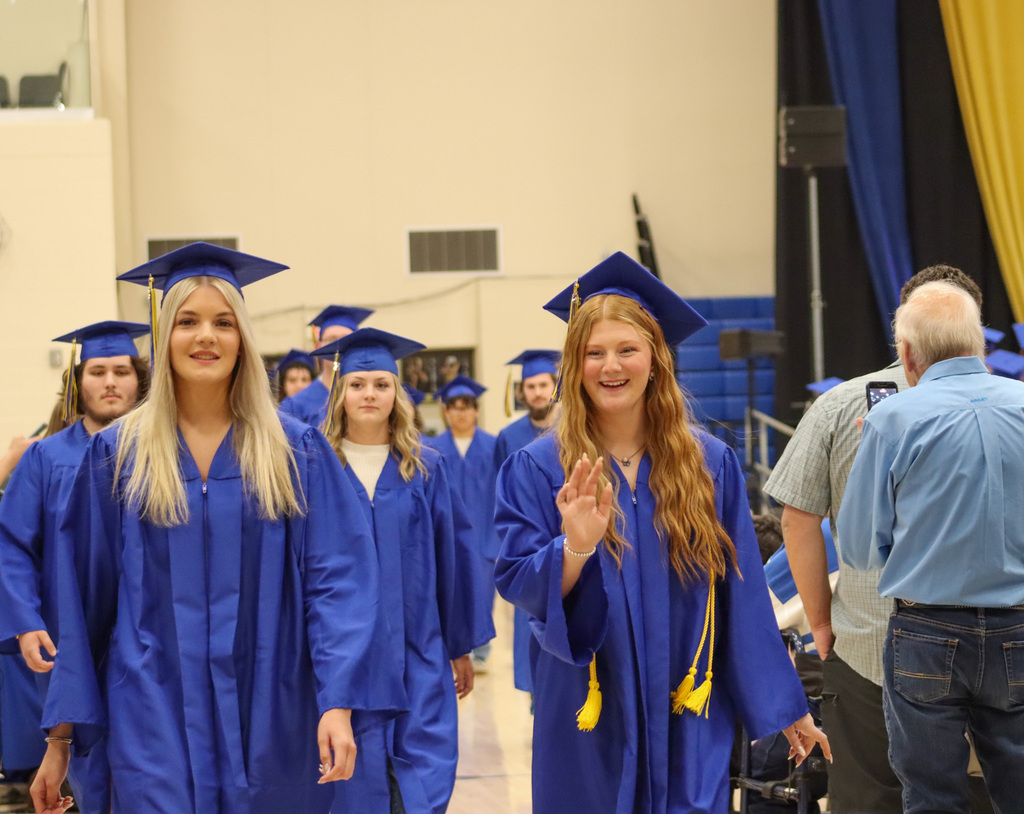A graduate waving at a loved one