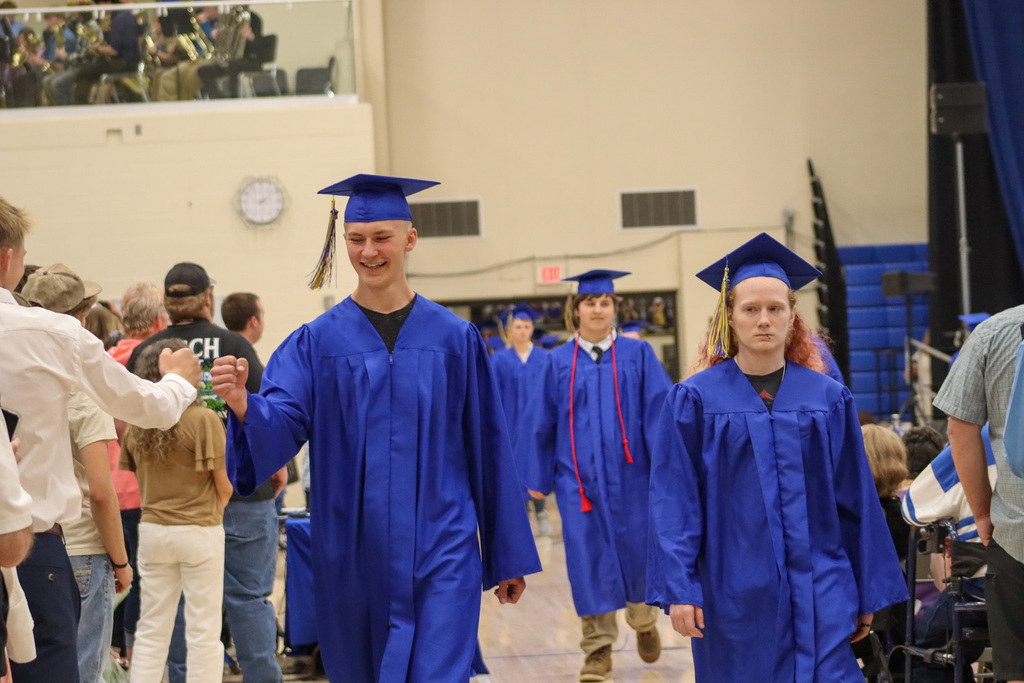 A graduate fist-bumping a loved one
