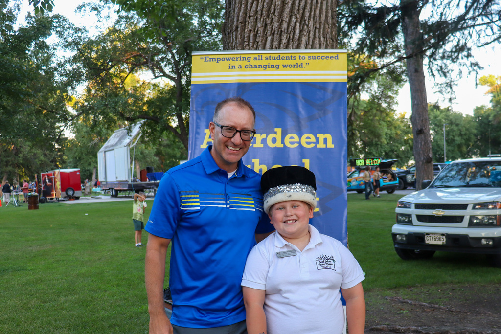 A student wearing a crown posing with his principal at National Night Out
