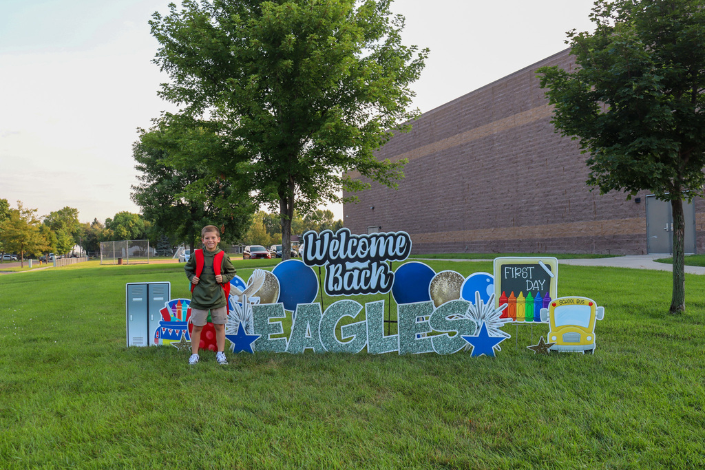 C.C. Lee student posing by a Welcome Back Eagles sign outside the school