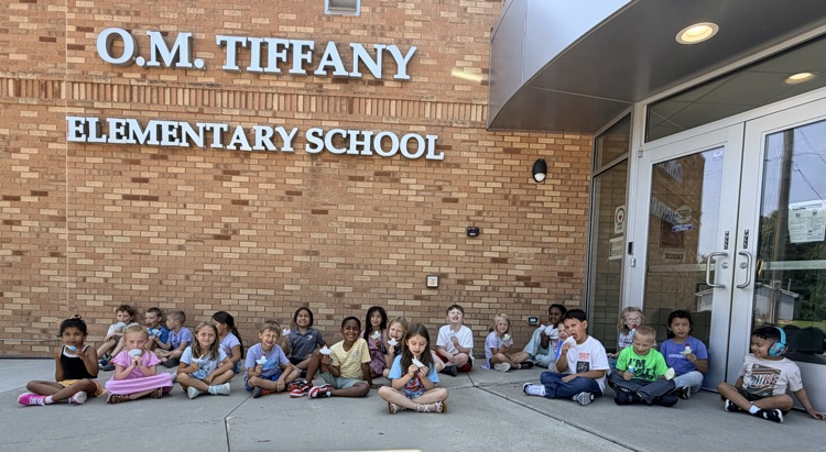 students sitting in front of a school enjoying popsicles