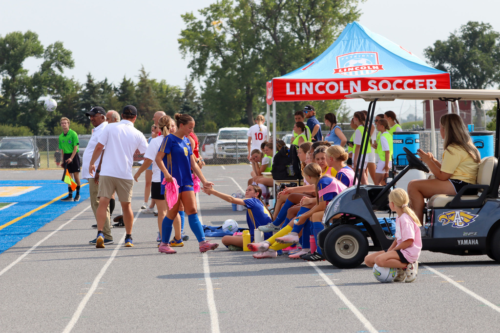 Girls soccer players giving each other a high five on the sidelines