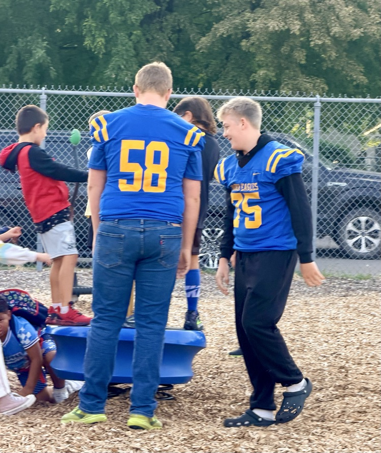 High school football players on playground with elementary school.