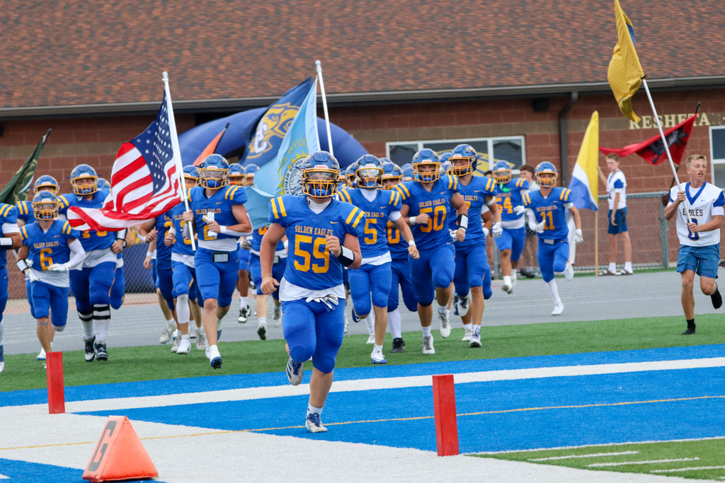 Football team running into the game carrying flags