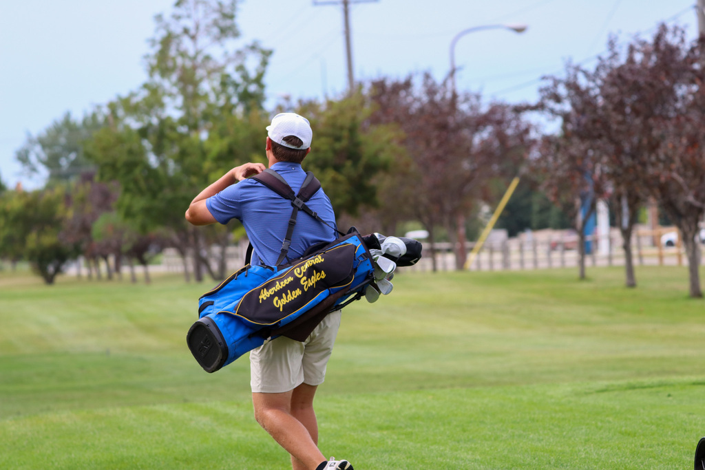 CHS boys golf team member walking on the golf course carrying his Aberdeen Central Golden Eagles bag
