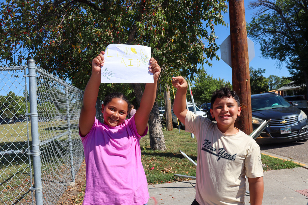 May Overby students holding a sign for their lemonade stand outside the school