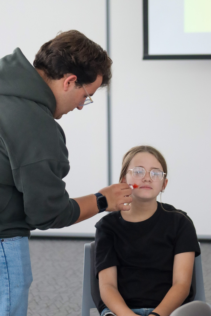 CHS actor demonstrating stage makeup with a student at the library
