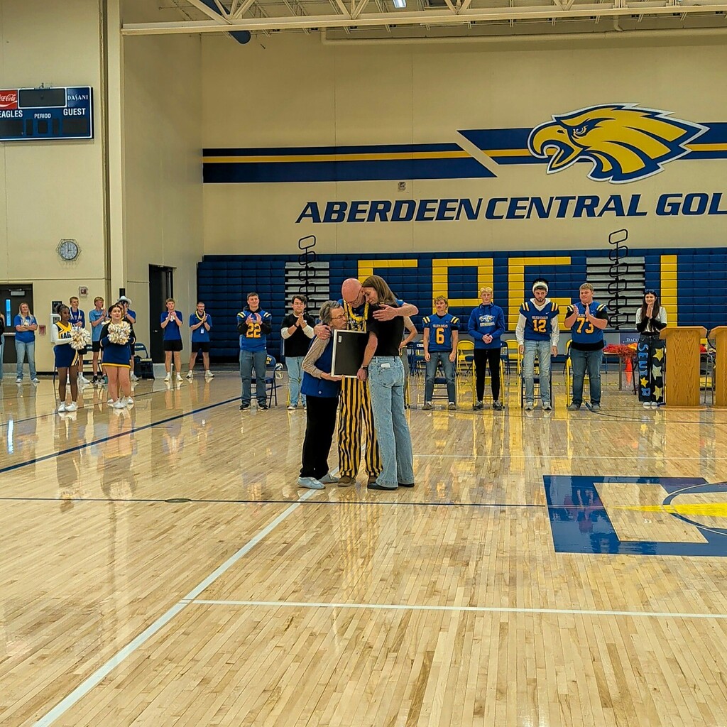 Dr. Uttermark hugging his family members after being recognized at the pep rally