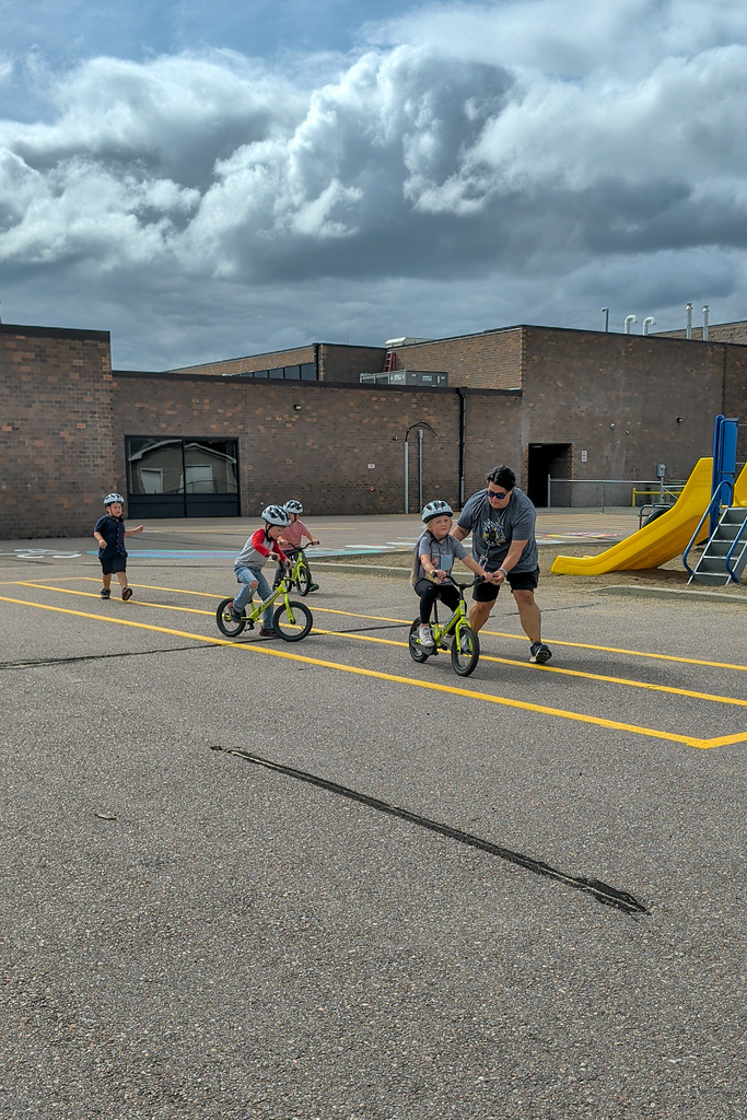 A C.C. Lee student riding a Strider bike during gym class with the help of Ms. Hansen