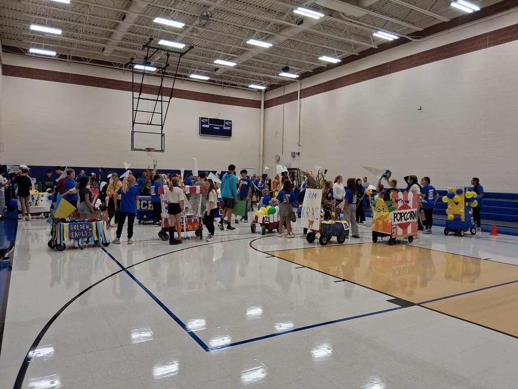 Several students lined up with their floats in the gym.