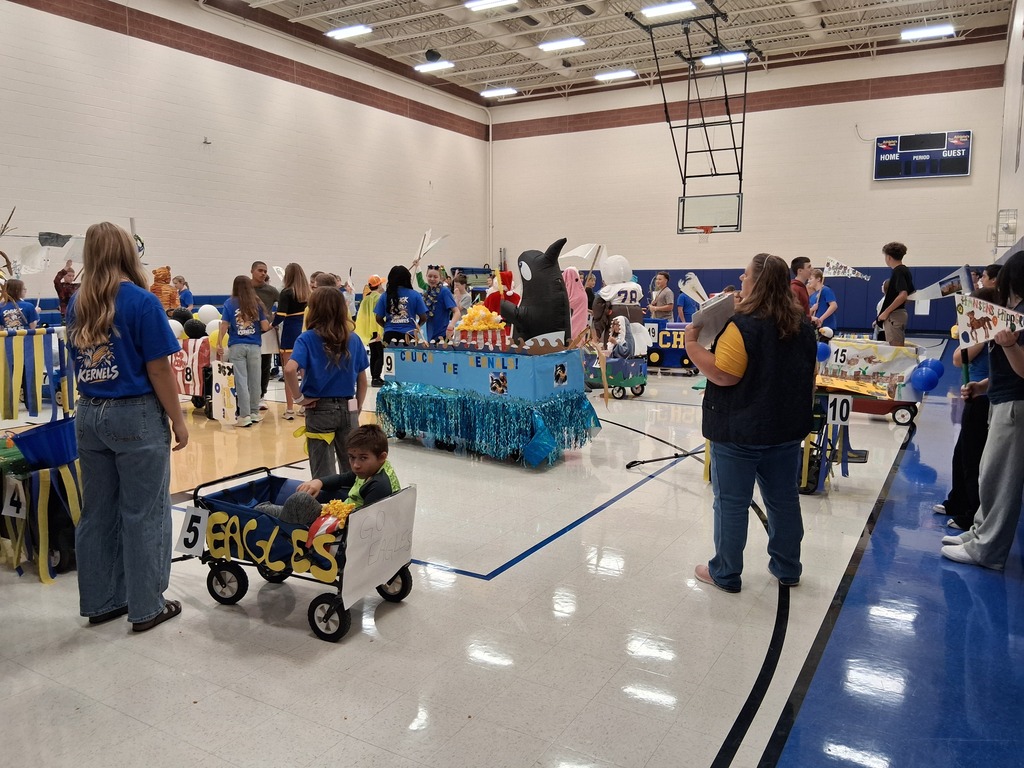 A gym full of students standing by their floats.