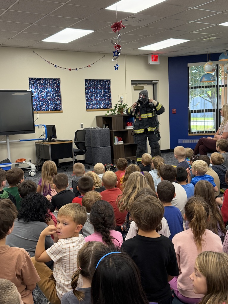 Firefighter in gear presenting to students.