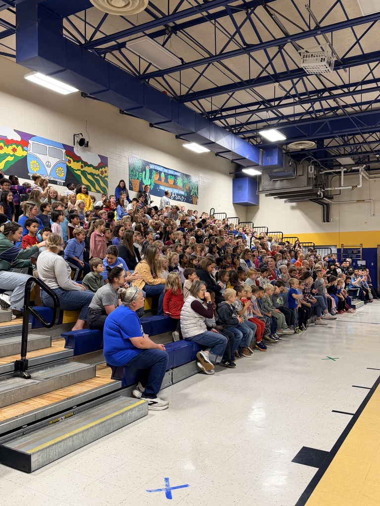 Students and staff in gym watching assembly.