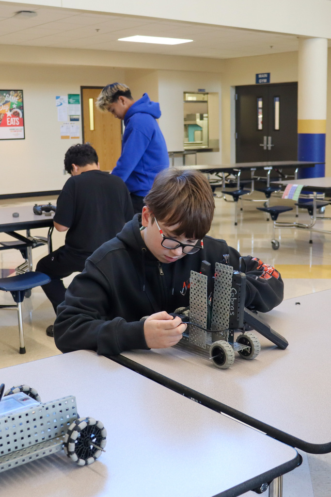 SMS 8th grader working on the car he made in robotics