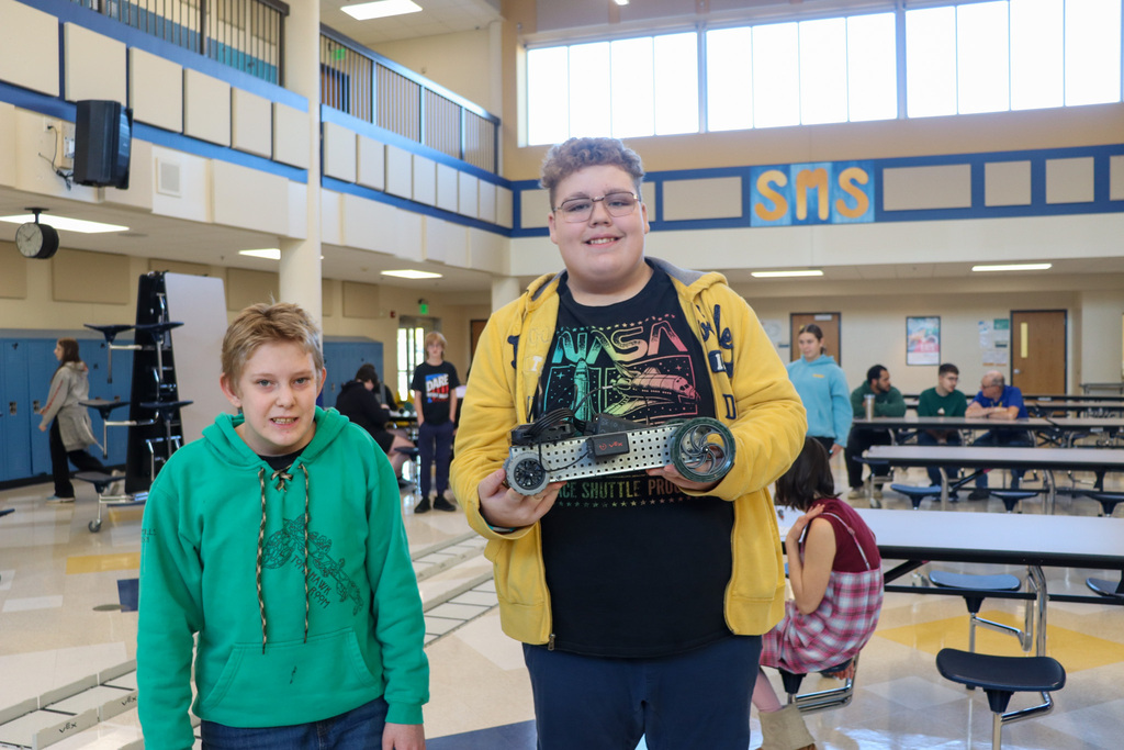SMS 8th graders holding the car they made in robotics