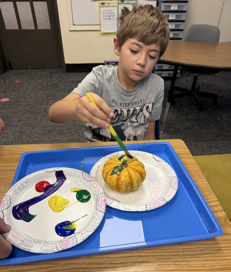 student painting pumpkin