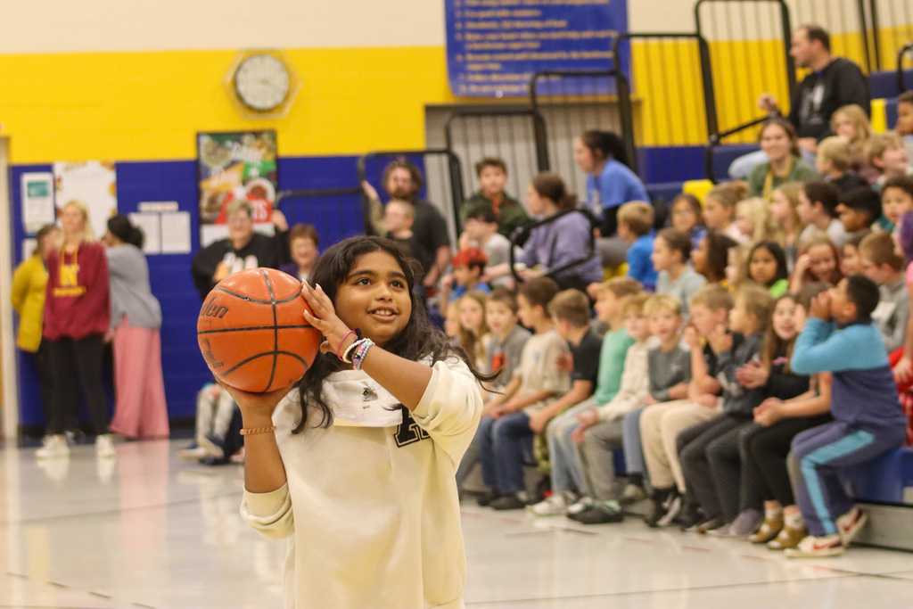 A 5th grader holding a basketball during the student-staff free throw contest