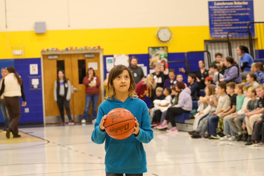 A 5th grader holding a basketball during the student-staff free throw contest