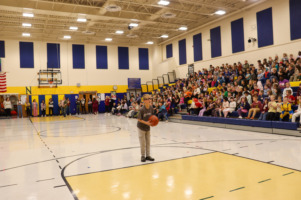 A 5th grader holding a basketball during the student-staff free throw contest