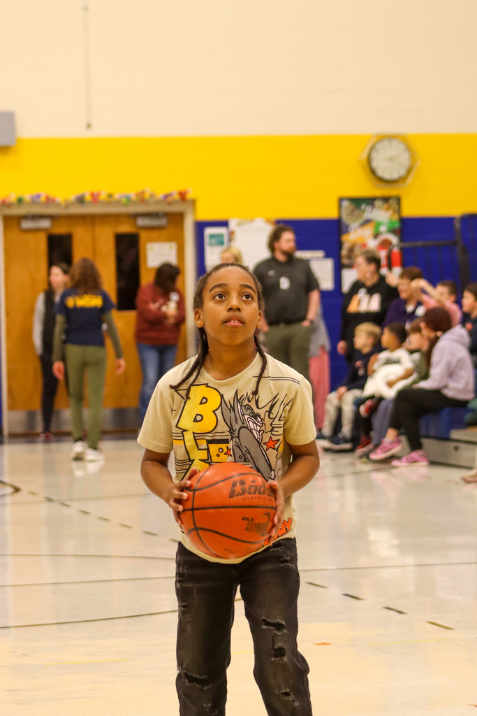 A 5th grader holding a basketball during the student-staff free throw contest
