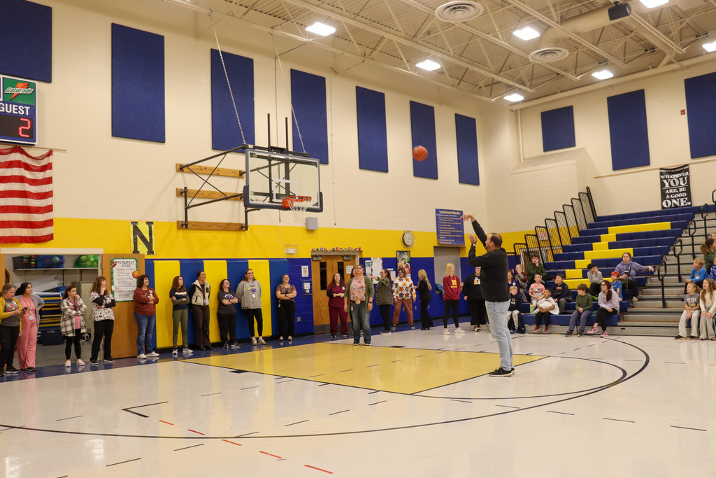 A teacher shooting a basketball during the student-staff free throw contest