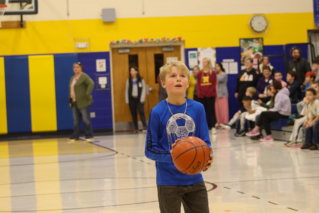 A 5th grader holding a basketball during the student-staff free throw contest