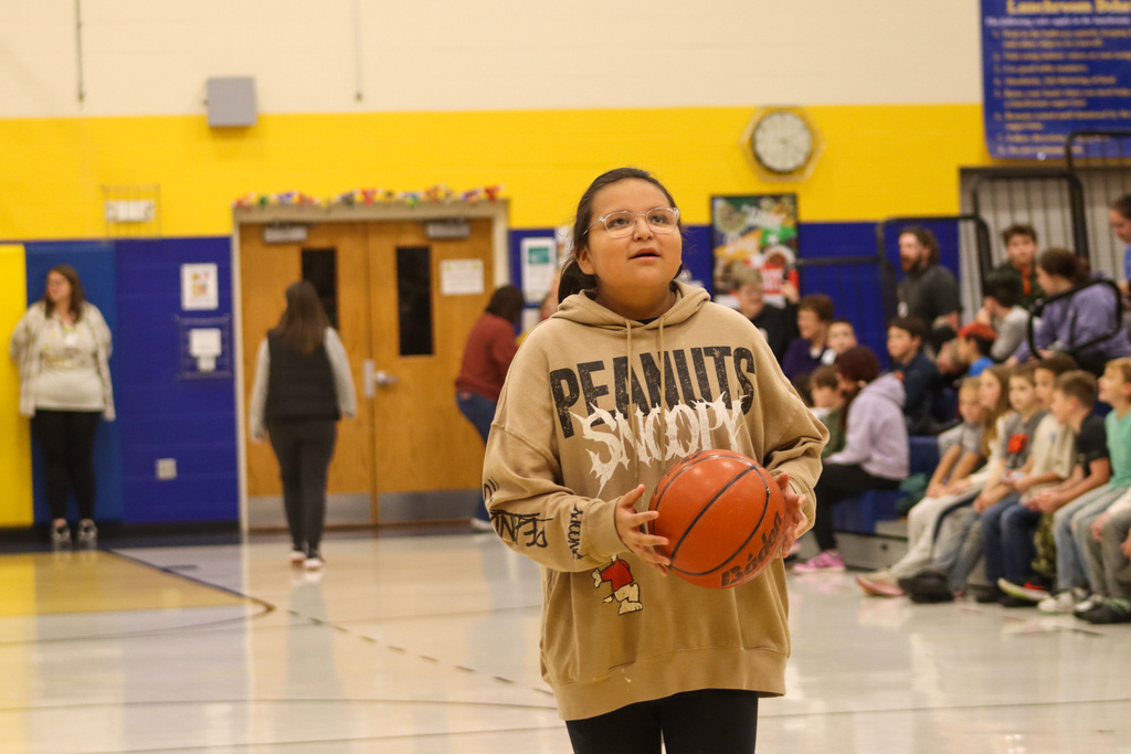A 5th grader holding a basketball during the student-staff free throw contest
