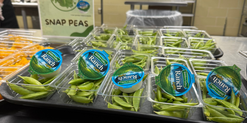 A photo of snap peas with individual ranch servings in an AISD caeteria