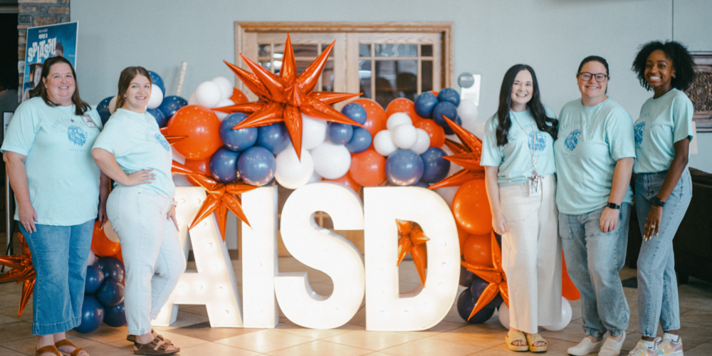 Stafford Teachers pose with an AISD-themed photo display