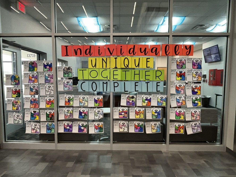 Student work displayed for Autism awareness, sign says individually unique together complete