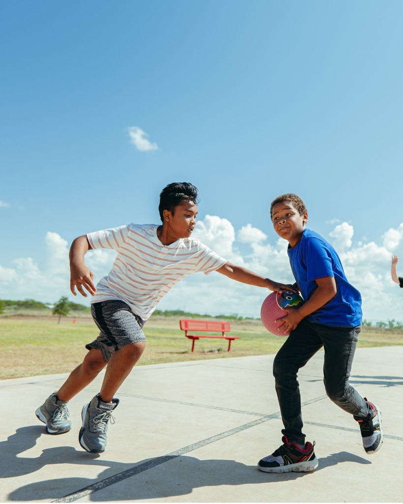A photo of two students playing basketball on an outdoor court
