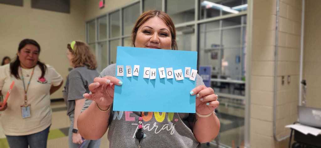 A teacher showing a sign that says, "beach towel."