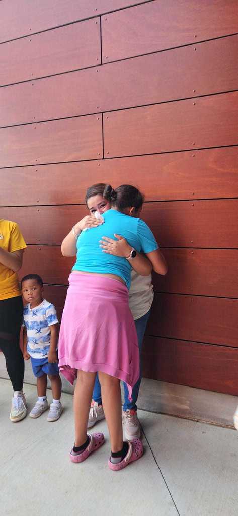 Two adults hug at the assembly