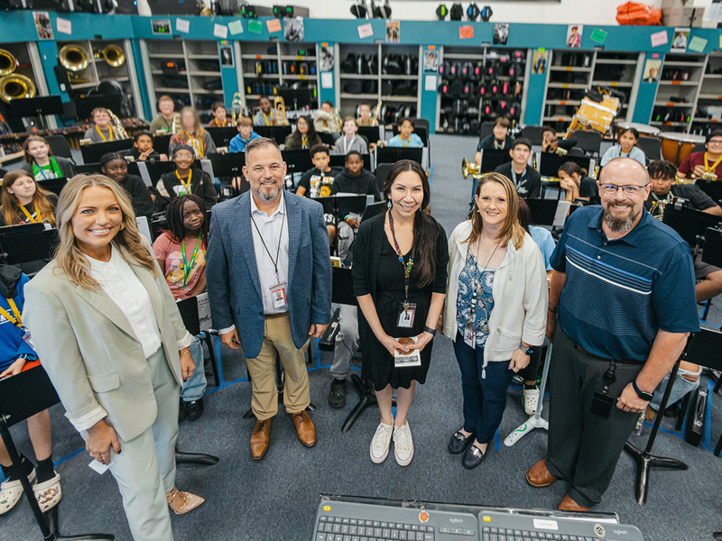 A photo of Pearl Gonzales, campus and district administrators, and student in the Clack band class