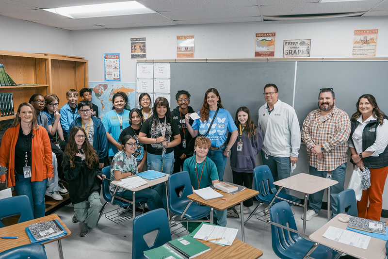 A photo of Mrs. Aich, her class, and members of the prize patrol