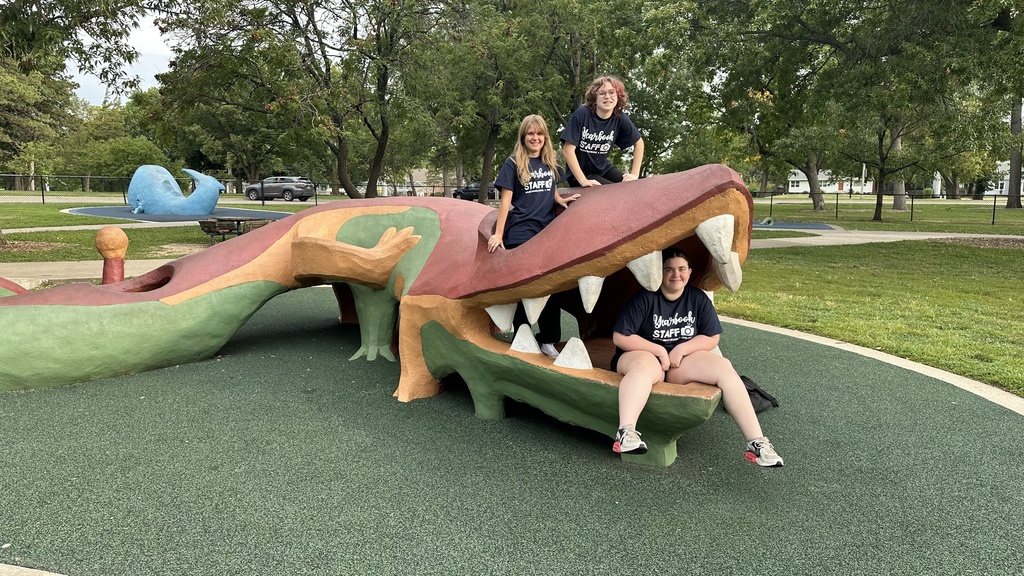 AMS Yearbook Staff sitting on and inside of a cement creature statue at the Topeka Zoo