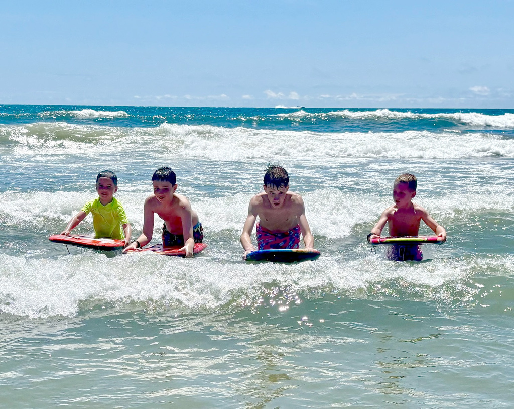 2 older cousins teach their younger cousins how to ride the waves on boogie boards in Wildwood, NJ