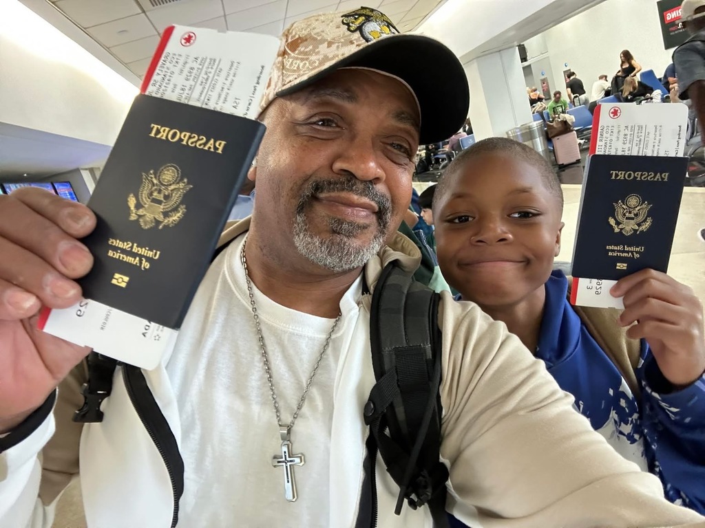Overlook 5th grader Dwain Garner and his PopPop hold up their passports at the airport before their trip to Korea