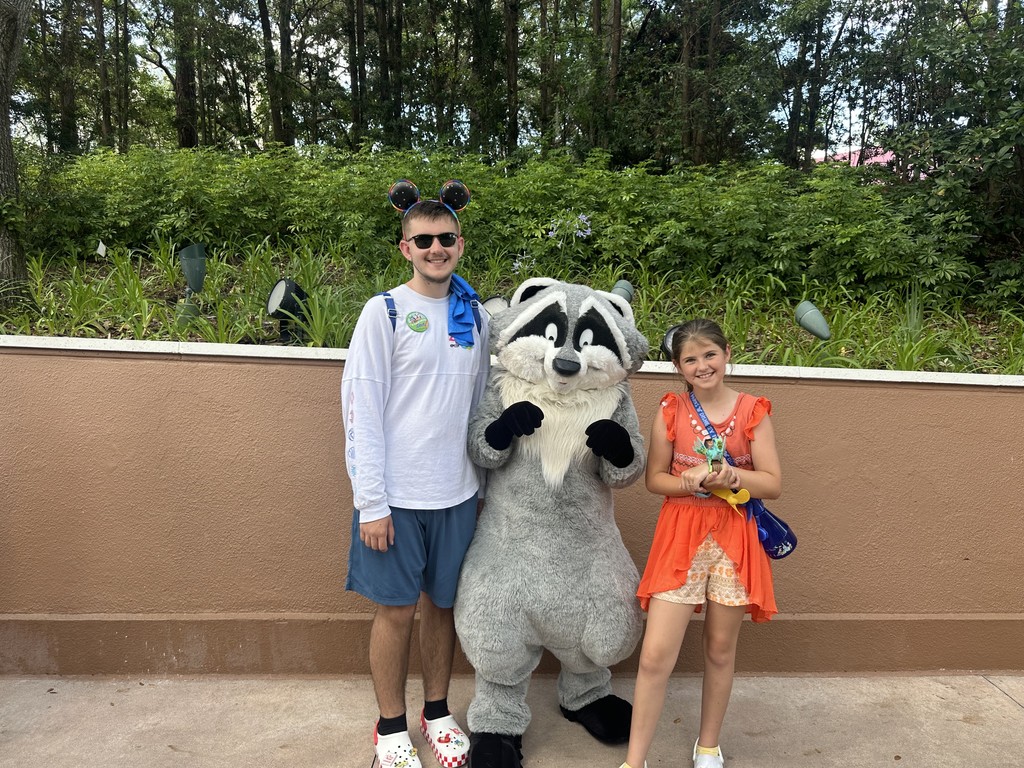 Danny and Abby pose with a racoon character while at Disney in Florida