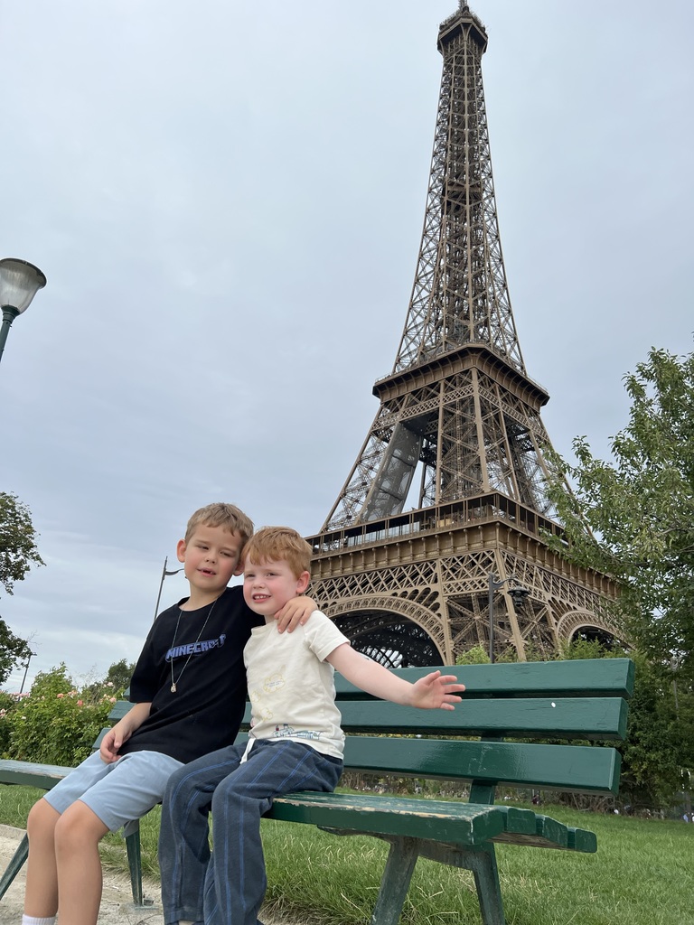 Leo and his brother Charlie pose on a bench with the Eiffel Tower in the background