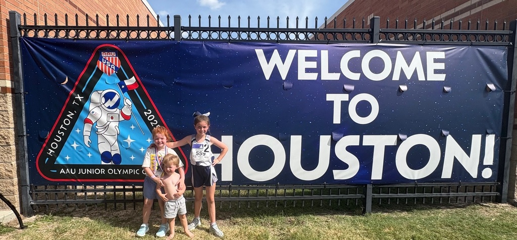 Lily with her sister and brother, standing in front of a banner which says "Welcome to Houston!" at the AAU Junior Olympics in Houston, Texas