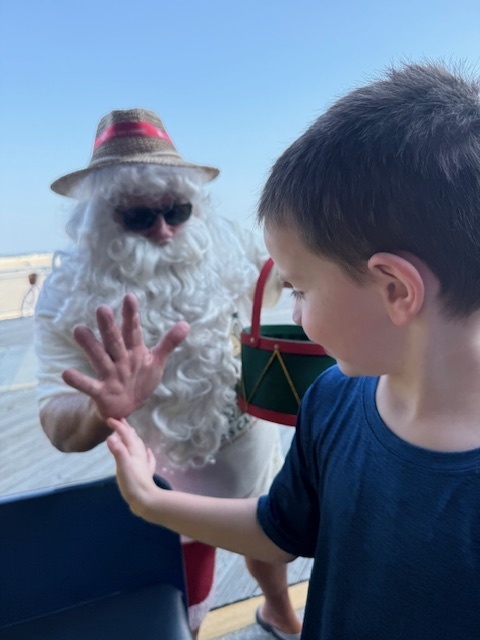 Mason gives a man dressed up as Santa in a white beard a "high five" to celebrate Christmas in July in Wildwood, NJ
