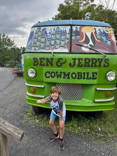 Jensen posed in front of a van painted with "Ben & Jerry's Cowmobile" , with a bright green front, graphics of ice cream containers and a cow on the windows