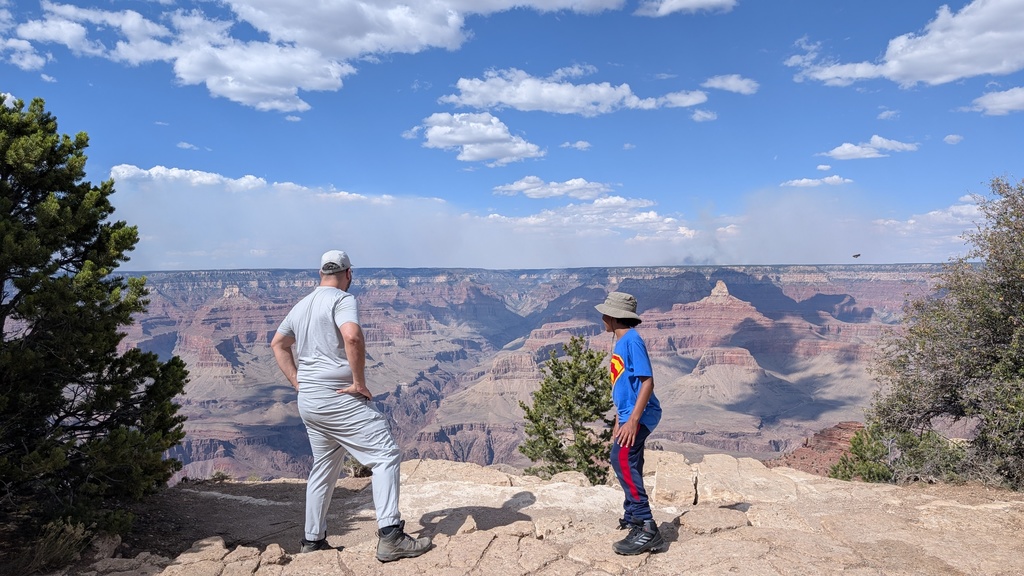 Jacob and a family member stand on an embankment, overlooking a huge expanse of rocky canyon