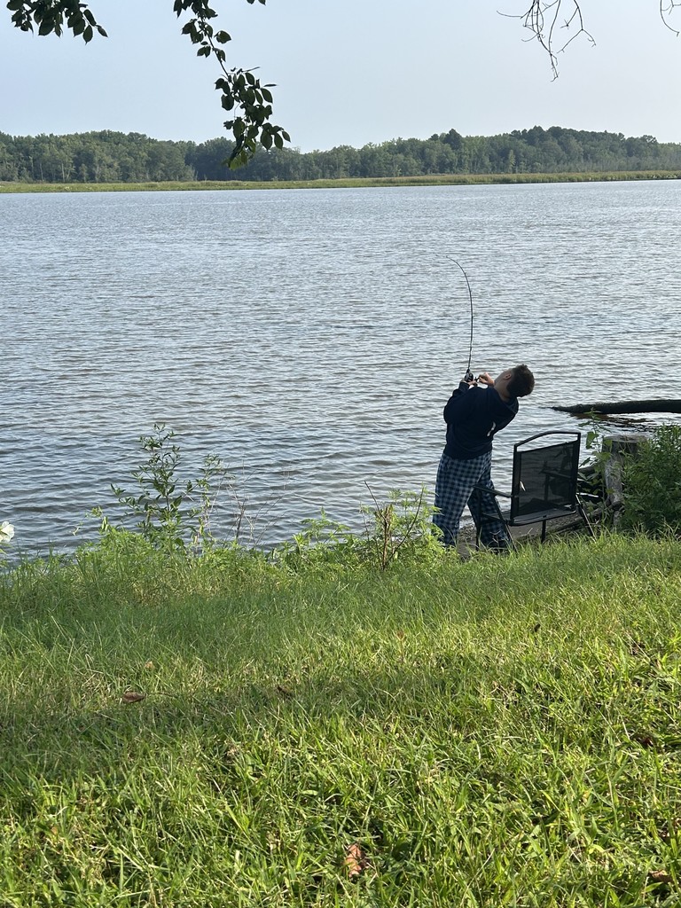 Dominic pulls his fishing rod along the shore of a body of water