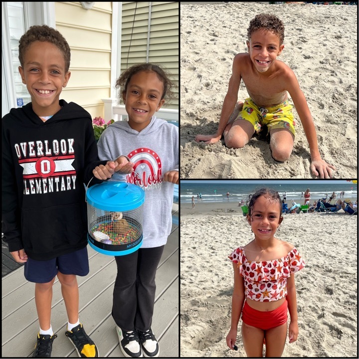 Nathan and Sophia posing holding their new hermit crabs, Nathan sitting on beach wearing yellow print bathing suit, Sophia standing on sand with beachgoers and ocean in background, wearing red and white swimsuit with seashells and starfish