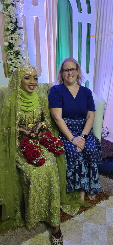 Burj Khalifa sits next to a beautifully adorned woman wearing a green dress and head garment adorned with beads, holding red roses